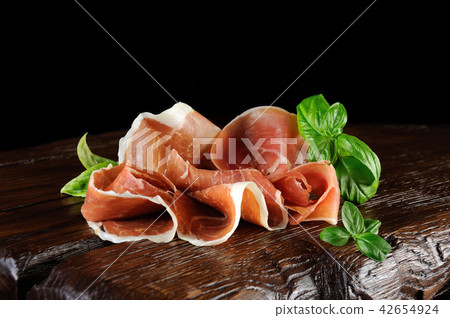 parma ham (jamon) sliced on a wooden board parma ham (jamon) sliced on a wooden board 42654924