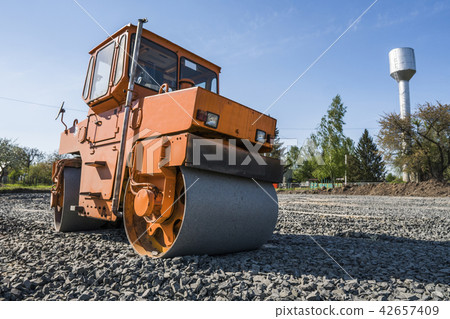 Orange light Vibration roller compactor standing on a stones at road construction and repairing Orange light Vibration roller compactor standing on a stones at road construction and repairing 42657409
