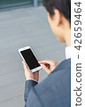 A businessman operating a smartphone 42659464