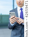 A businessman operating a smartphone 42659471