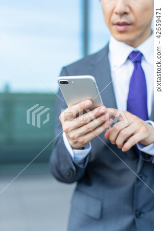 A businessman operating a smartphone A businessman operating a smartphone 42659471