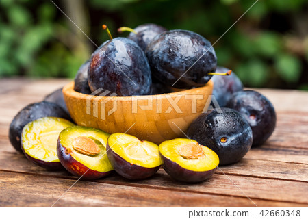Fresh ripe plums and halves in wooden bowl close Fresh ripe plums and halves in wooden bowl close 42660348