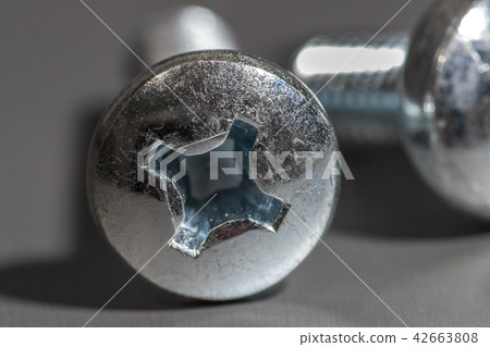 Two heads of screws on a gray background. Two heads of screws on a gray background. 42663808
