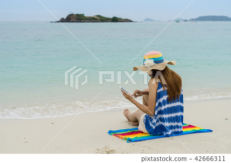 Young woman using mobile phone at the beach Young woman using mobile phone at the beach 42666311