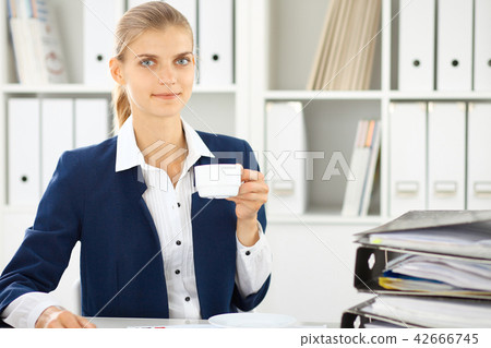 Happy business woman or female accountant having some minutes for coffee and pleasure at working 42666745