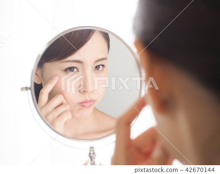 A woman troubled watching a mirror 42670144