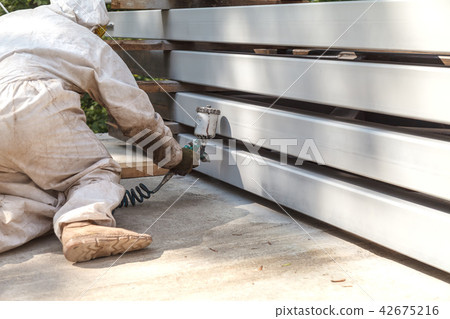 A man paints a metal tube with a pulverizer A man paints a metal tube with a pulverizer 42675216