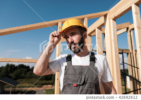 The man is a builder on the roof of a wooden frame house. The man is a builder on the roof of a wooden frame house. 42692612