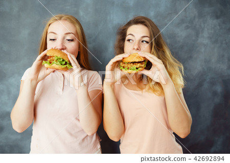 Two cute young women eating delicious burgers Two cute young women eating delicious burgers 42692894