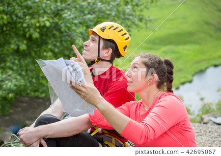 Side view of female tourist and man in yellow helmet against background of green vegetation Side view of female tourist and man in yellow helmet against background of green vegetation 42695067