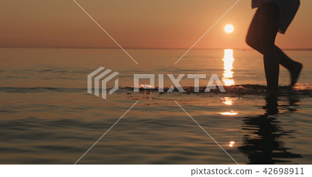 closeup young female legs walking in shallow water on a beach 42698911