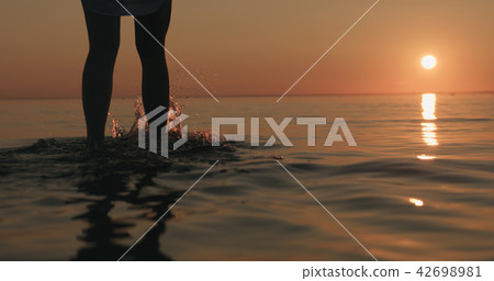 closeup young female legs walking in shallow water on a beach 42698981