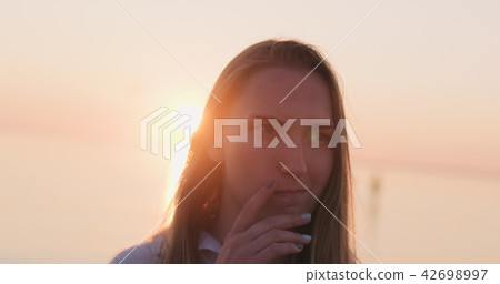 teenage girl standing on a beach at sunset and thinking about something teenage girl standing on a beach at sunset and thinking about something 42698997