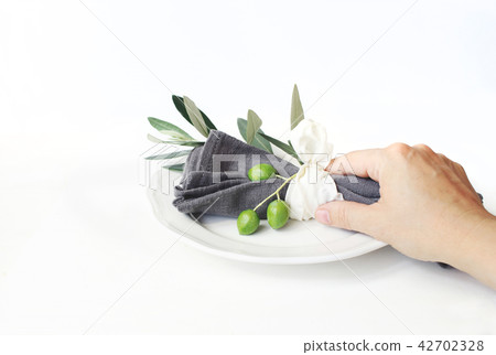 Woman hand holding grey linen napkin decoted by olive branch and silk ribbon. Festive table summer 42702328
