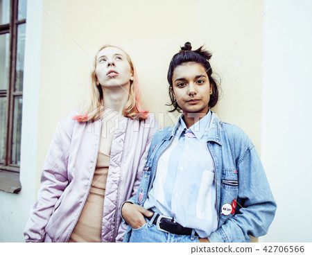 Two teenage girls infront of university building smiling, having 42706566