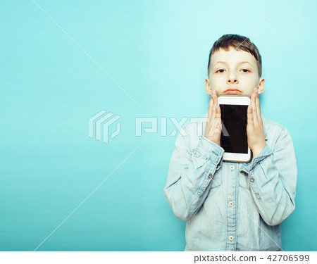 little cute boy posing emotional on blue background with smartph 42706599