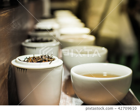 White tea pot and cups with the black tea leaves White tea pot and cups with the black tea leaves 42709610