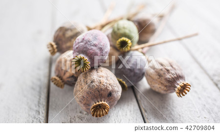 Poppy heads freely lying on a wooden board. 42709804