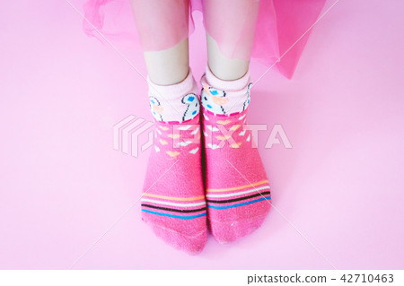Young girl and legs in pink socks on pink Young girl and legs in pink socks on pink 42710463