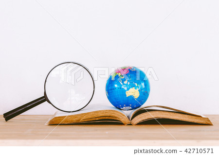 Global ball on book and magnifying glass Global ball on book and magnifying glass 42710571