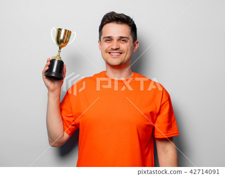 man in orange t-shirt with golden cup 42714091