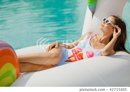 A young beautiful girl with a beautiful figure in a swimsuit and sunglasses is resting and tanning A young beautiful girl with a beautiful figure in a swimsuit and sunglasses is resting and tanning 42715805