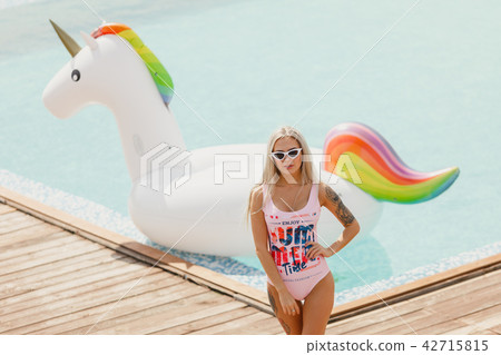 A young beautiful girl with a beautiful figure in a swimsuit and sunglasses is resting and tanning 42715815