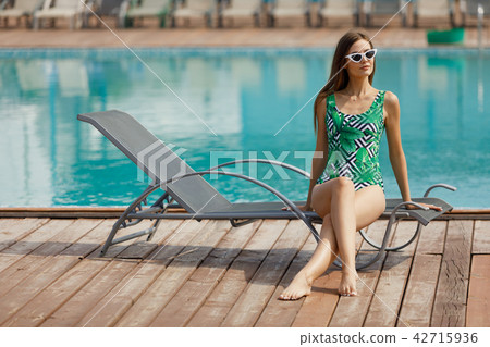 Slim fashion model in a swimsuit posing near the pool 42715936