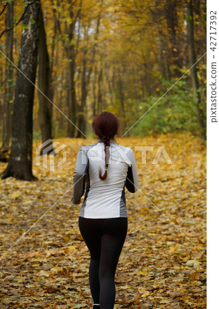 Image from back in full growth of girl running along autumn foliage 42717392