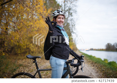 Photo of smiling brunette in helmet and with backpack showing ok on bicycle Photo of smiling brunette in helmet and with backpack showing ok on bicycle 42717439