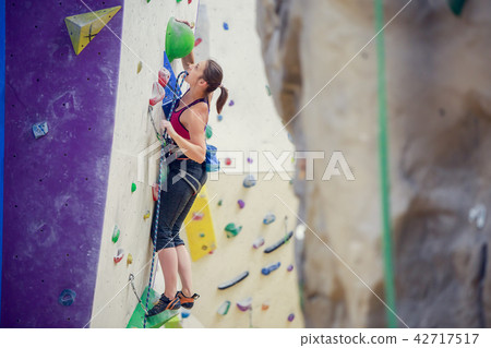 Photo of young woman with safety rope practicing on climbing wall 42717517
