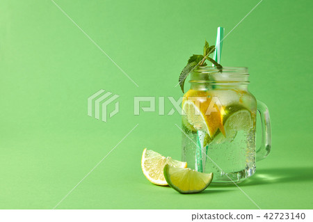 Mason jar with fresh homemade sparkling lemonade with citrus fruits, ice cubes, sprig of mint and 42723140