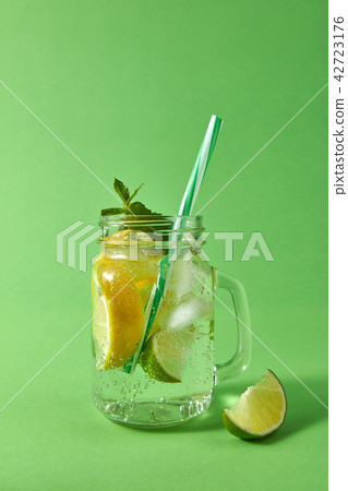 Mason jar with sparkling ackoholic mojito with ice, slices of lime and lemon, leaf of mint with 42723176