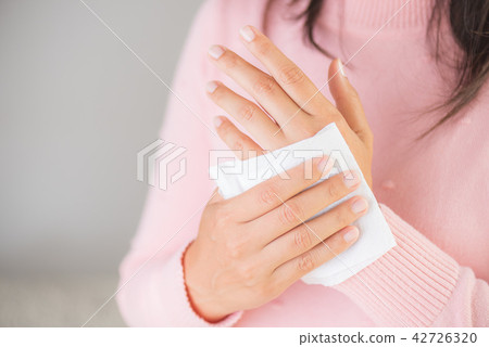 Woman cleaning her hands with a tissue.  42726320