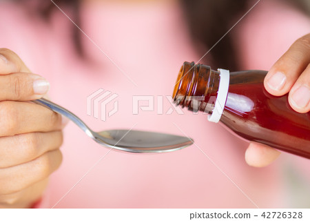 Woman hand pouring antipyretic syrup from bottle 42726328