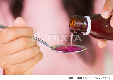 Woman hand pouring antipyretic syrup from bottle 42726329