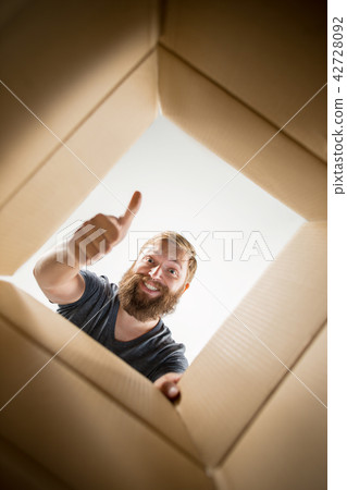 Man unpacking and opening carton box and looking inside Man unpacking and opening carton box and looking inside 42728092