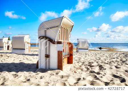 Hooded wicker basket chairs on a beach. 42728717