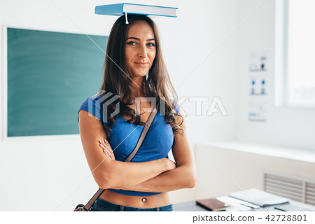 Portrait of female student holding book on her head 42728801