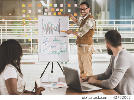 Young Talented Guy at Board Draws Infographics. Young Talented Guy at Board Draws Infographics. 42732062