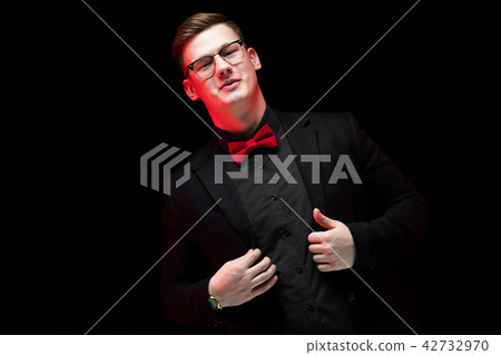 Portrait of confident handsome elegant responsible businessman holding hands on his jacket on black 42732970