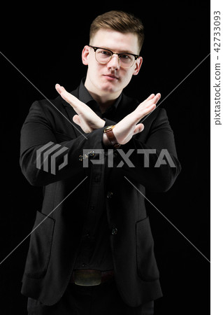 Portrait of confident handsome elegant responsible businessman showing stop gesture on black Portrait of confident handsome elegant responsible businessman showing stop gesture on black 42733093