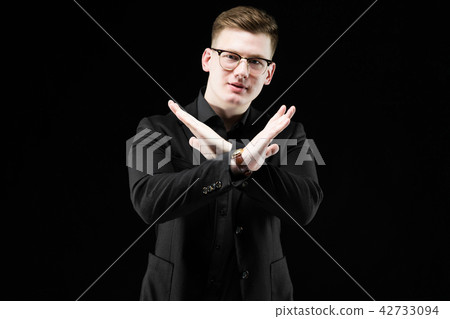 Portrait of confident handsome elegant responsible businessman showing stop gesture on black Portrait of confident handsome elegant responsible businessman showing stop gesture on black 42733094