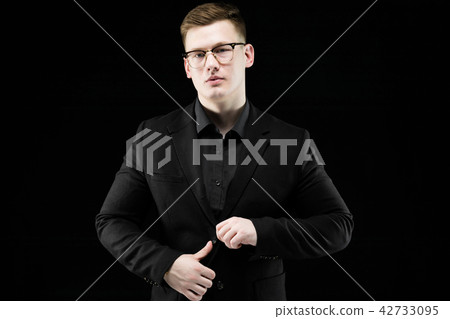 Portrait of confident handsome elegant responsible businessman with hand on his jacket on black Portrait of confident handsome elegant responsible businessman with hand on his jacket on black 42733095