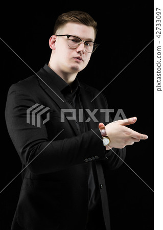 Portrait of confident handsome elegant responsible businessman looking at watches on black Portrait of confident handsome elegant responsible businessman looking at watches on black 42733097