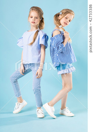 Girls twins in light blue clothes are posing on a blue background. 42733386