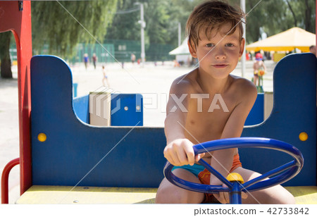 The boy is driving a children's car. Playground. 42733842
