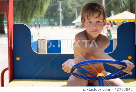 The boy is driving a children's car. Playground. 42733843
