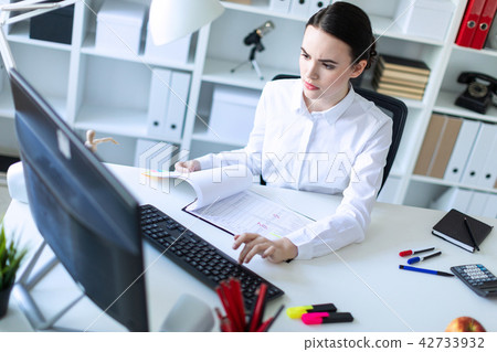 Young girl in the office working with documents at the computer. 42733932