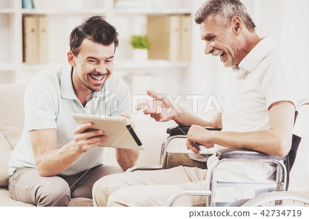 Laughing Young Son Showing Tablet to Father. 42734719
